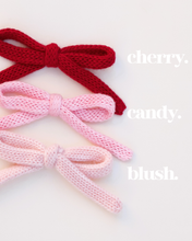 Load image into Gallery viewer, Three knitted bows in red, pink, and blush on a white background.