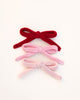 Three knitted bows in red, pink, and white on a white background
